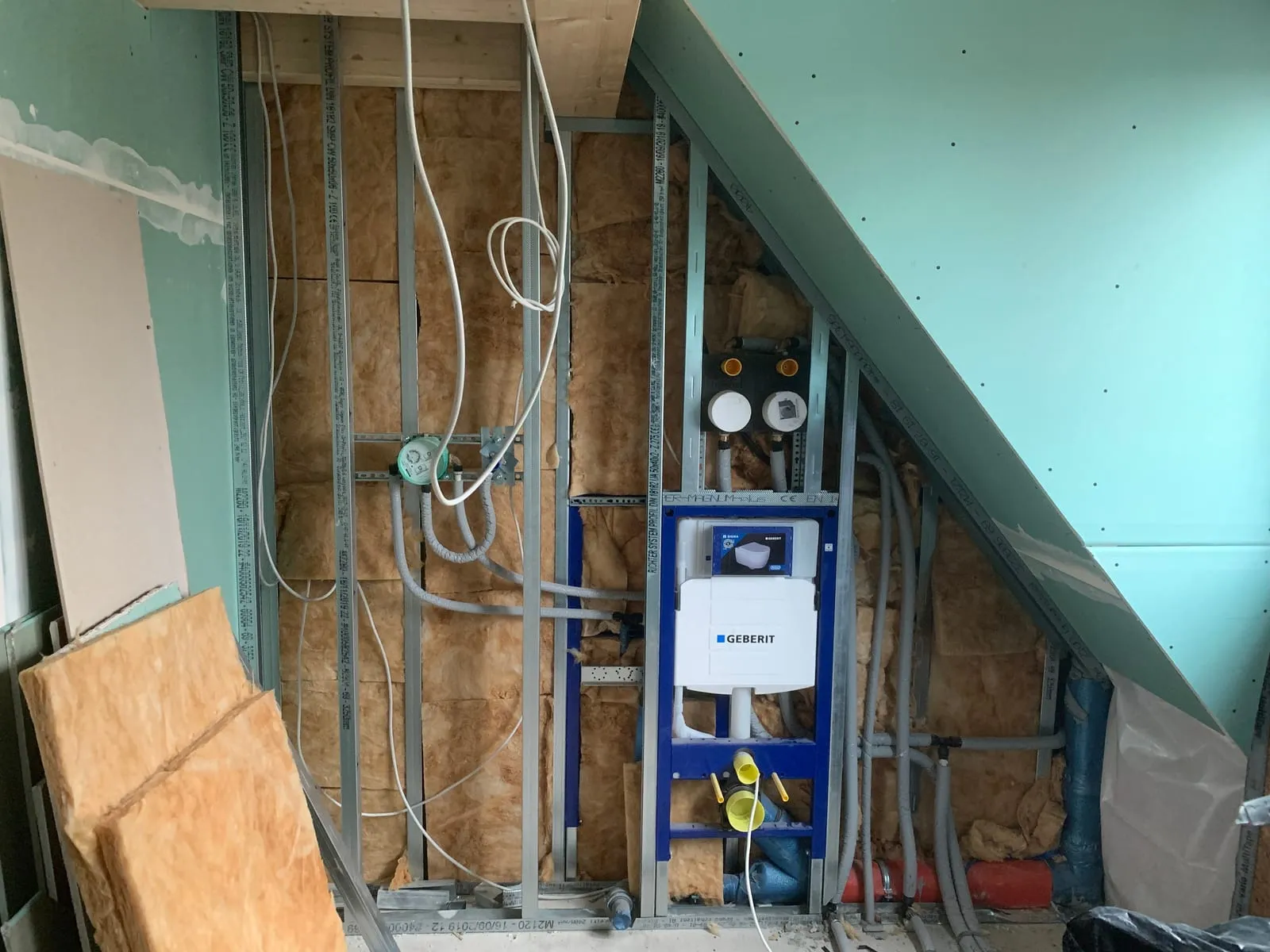 Offene Installationswand im Bad mit Vorwandelementen, Wasserleitungen und imprägnierten Platten