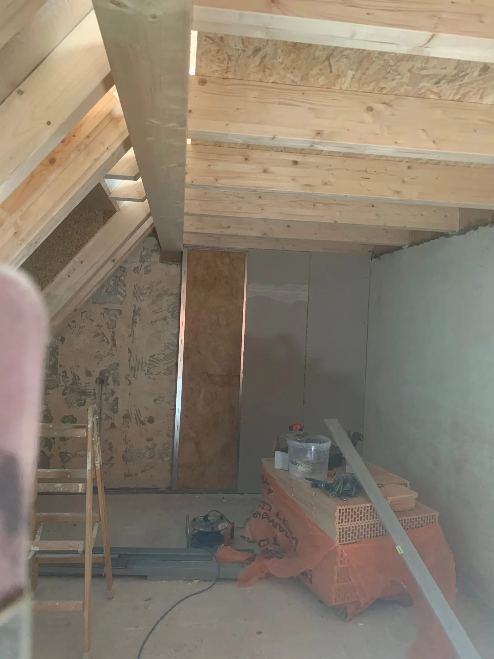 Dachgeschoss im Ausbau, Schrägen teilweise mit Gipskarton beplankt, Holzbalken sichtbar