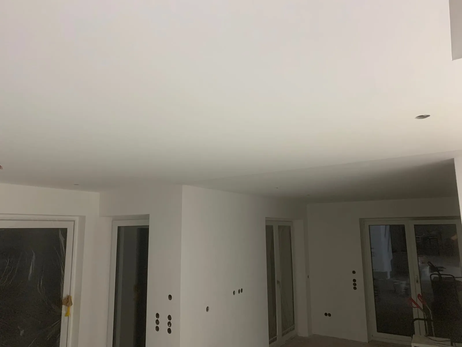 Fertig gespachtelter, weiß grundierter Wohnraum mit glatten Wänden und drei Fensteröffnungen