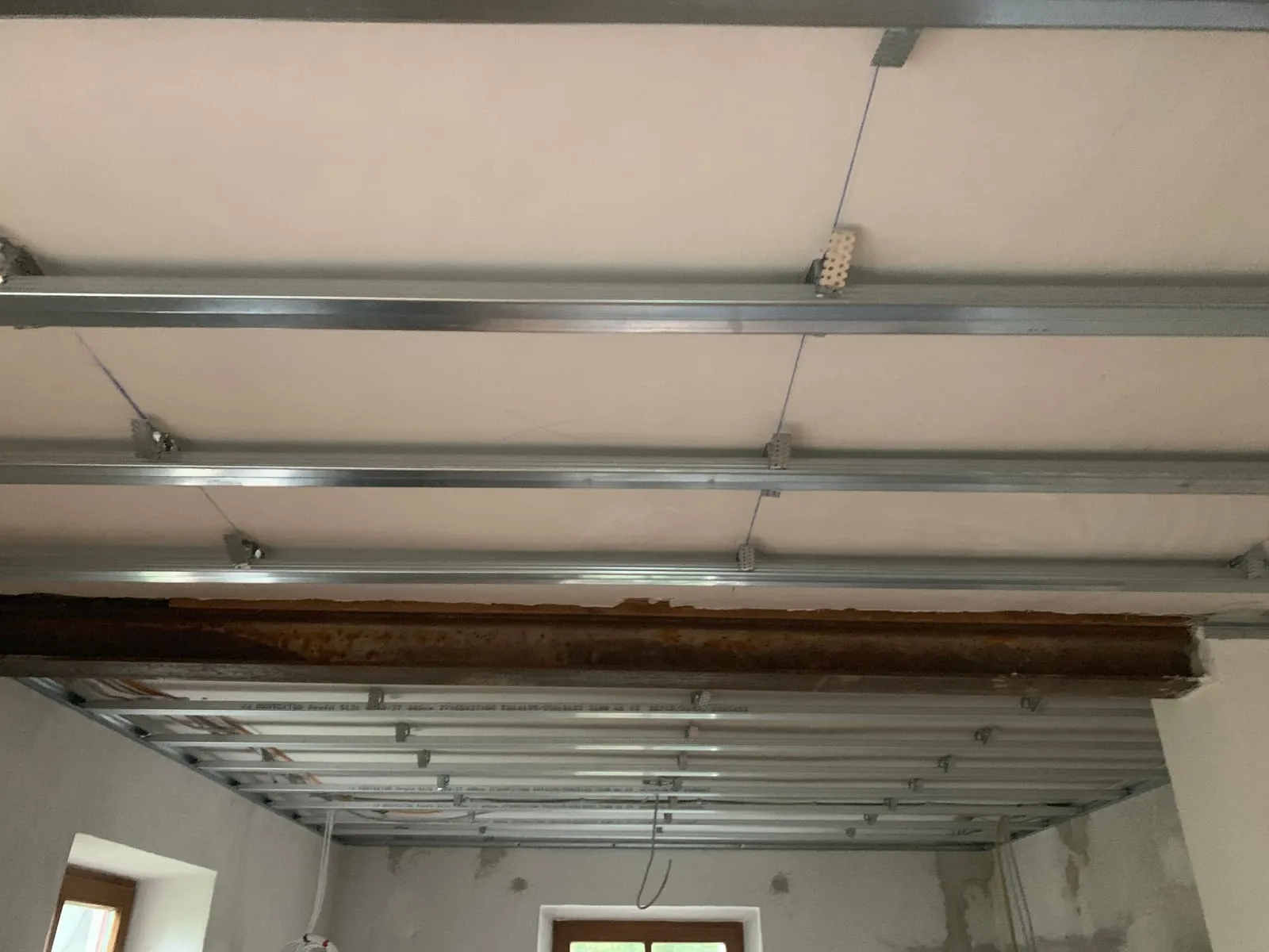 Deckenprofile einer abgehängten Decke im Altbau, sichtbarer alter Holzbalken wird integriert