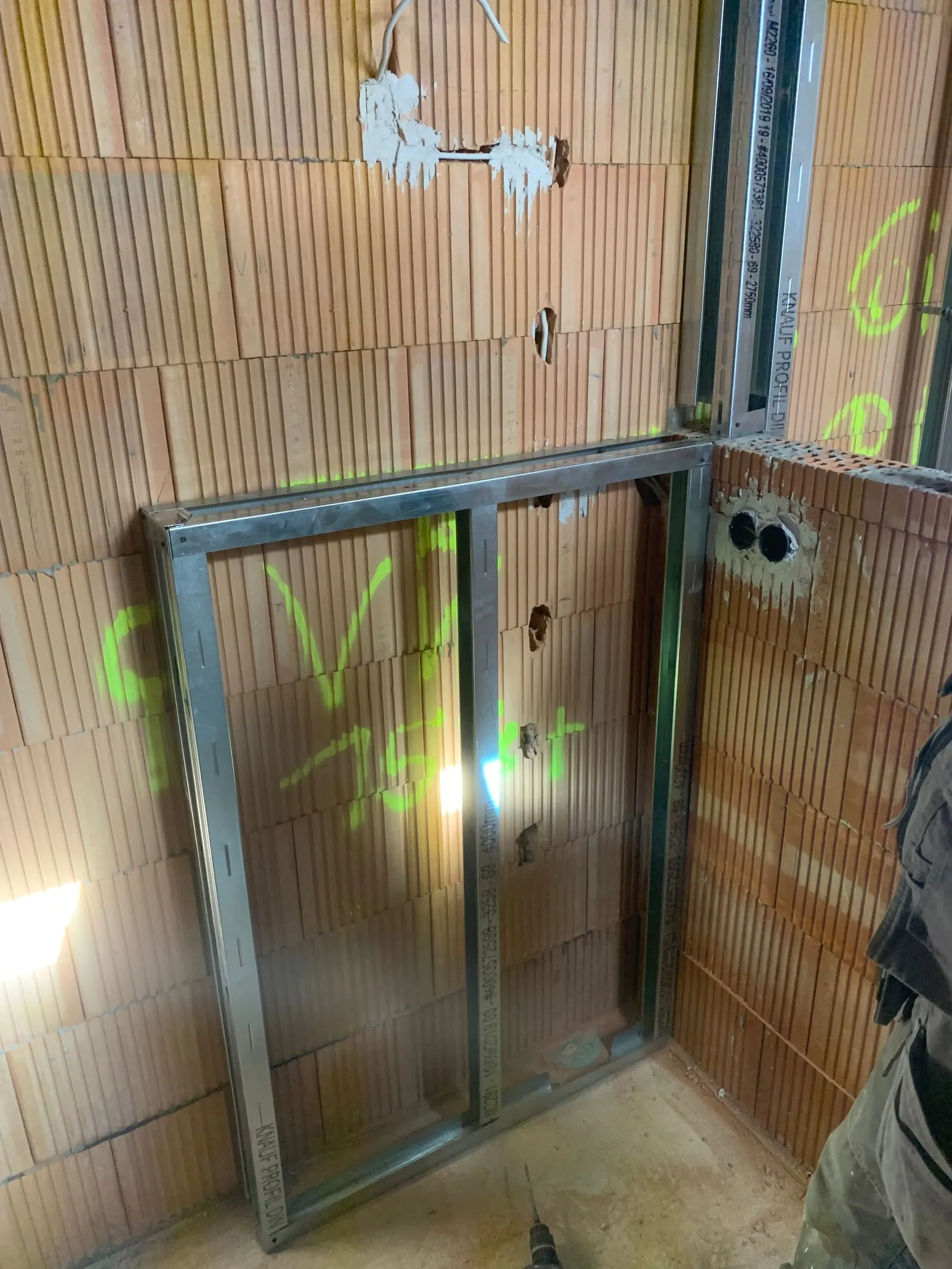 Metallständerwerk mit ausgesteifter Türöffnung vor einer Ziegelwand im Rohbau